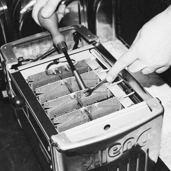 Hands repairing the interior mechanism of a Dualit DA0144 6 Slice Vario Toaster.